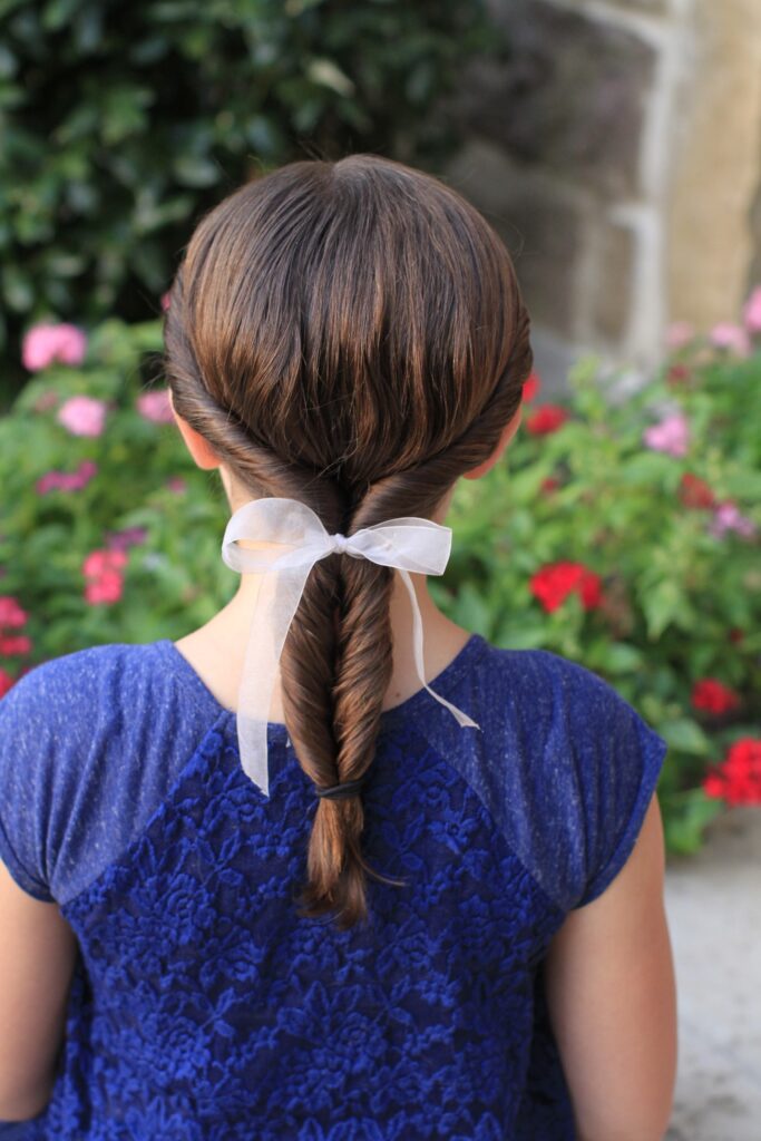 Back view of a young girl outside modeling “Double-twist" ponytail