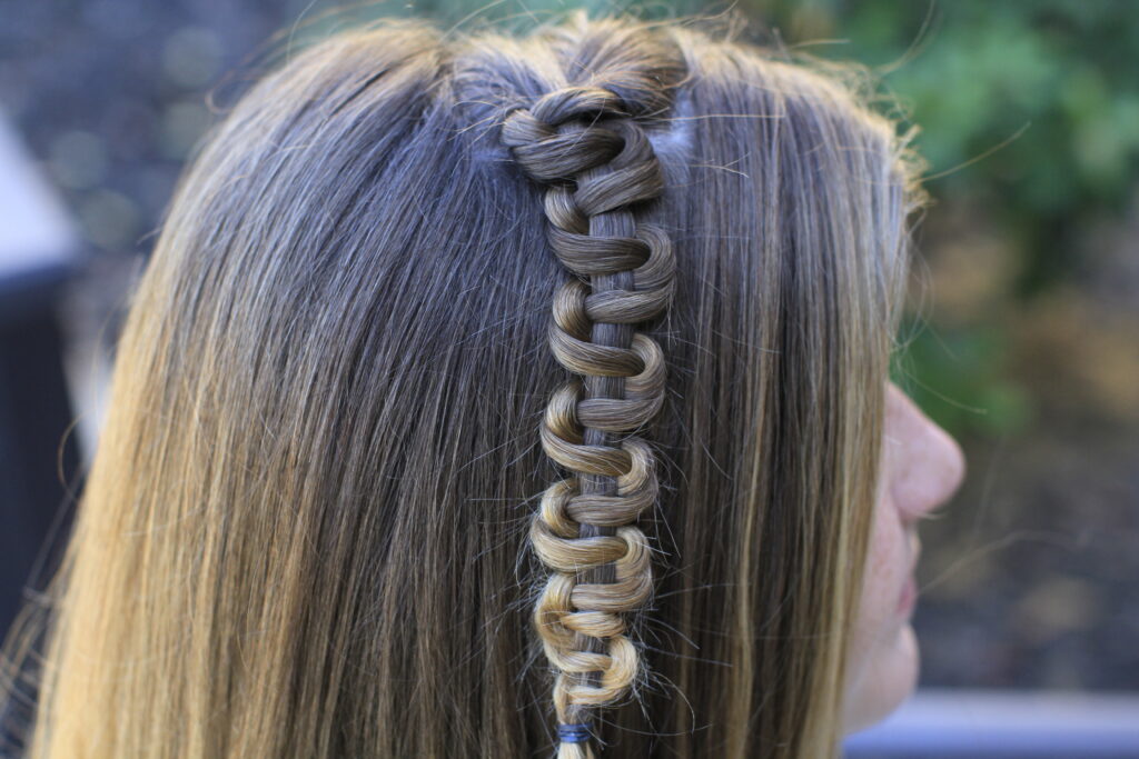 Side view of young girl modeling "Teen Slide-Up Braid" hairstyle outside