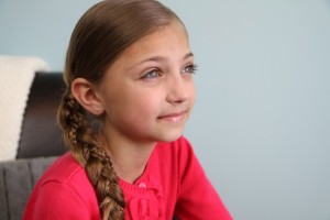 Portrait view of a young girl modeling the Micro-Braid Accented Side Braid | Braided Hairstyles