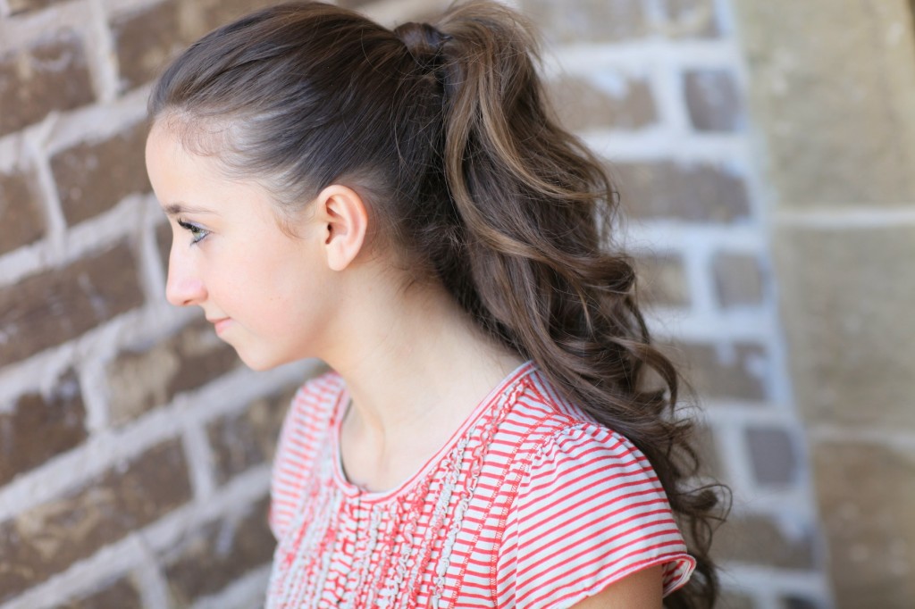 Young girl outside modeling a red shirt modeling the "perfect ponytail" 