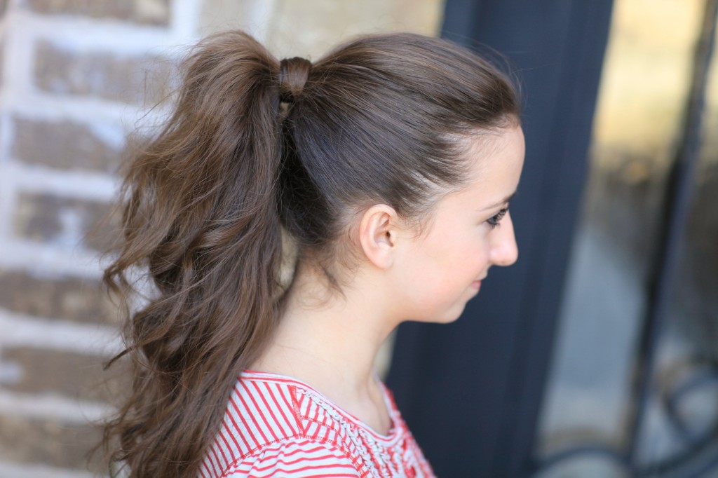 Young girl outside modeling a red shirt modeling the "perfect ponytail" 