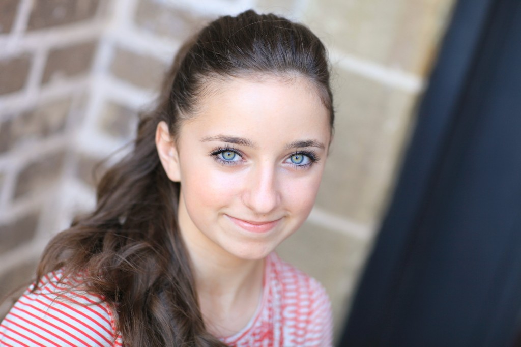 Young girl outside modeling a red shirt modeling the "perfect ponytail" 