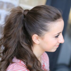 Young girl outside modeling a red shirt modeling the "perfect ponytail"