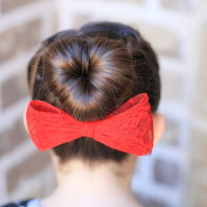 Young girl outside modeling "Love Bun" with a red bow in her hair | Valentine's Day Hairstyles