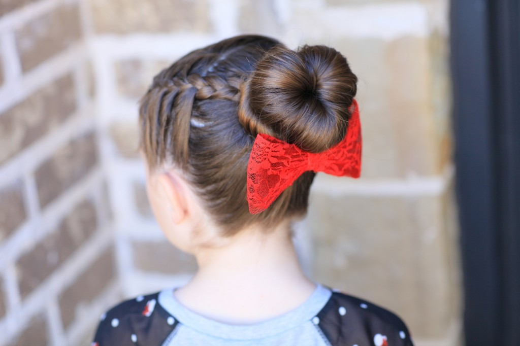 Young girl outside modeling "Love Bun" with a red bow in her hair | Valentine's Day Hairstyles