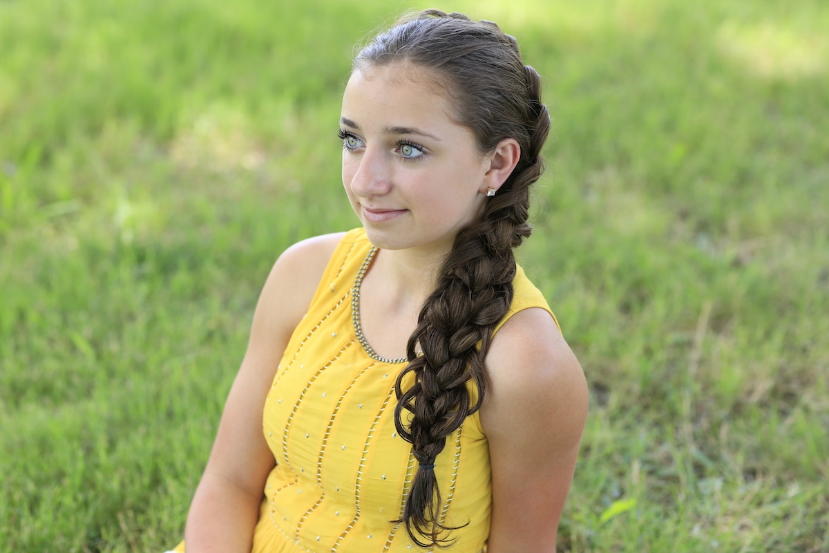 Young girl outside in a yellow shirt modeling "Diagonal French Loop Braid" hairstyle