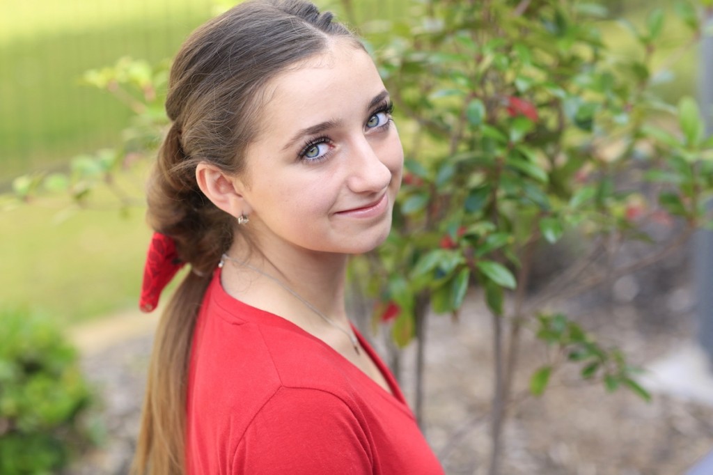 Young girl wearing a red shirt modeling Banded Puff Braid