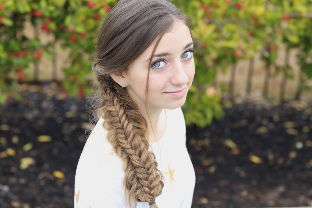 Young girl outside wearing a white shirt modeling Messy Split Fishtail Braid