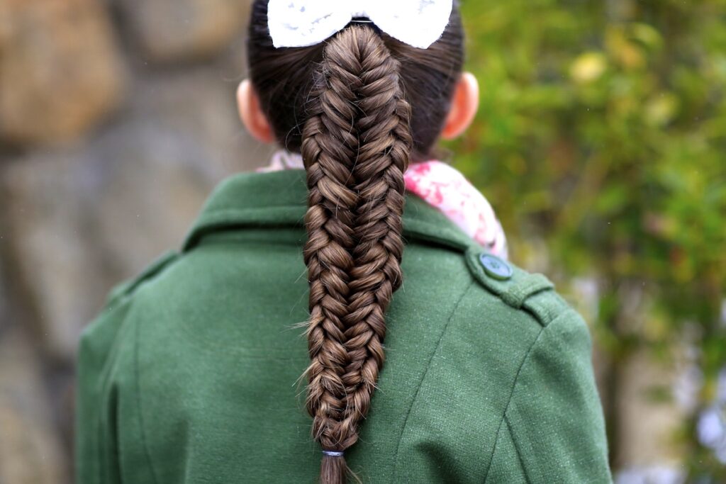 Young girl outside in a winter coat modeling Twisted Edge Fishtail Combo | Braid and Updo