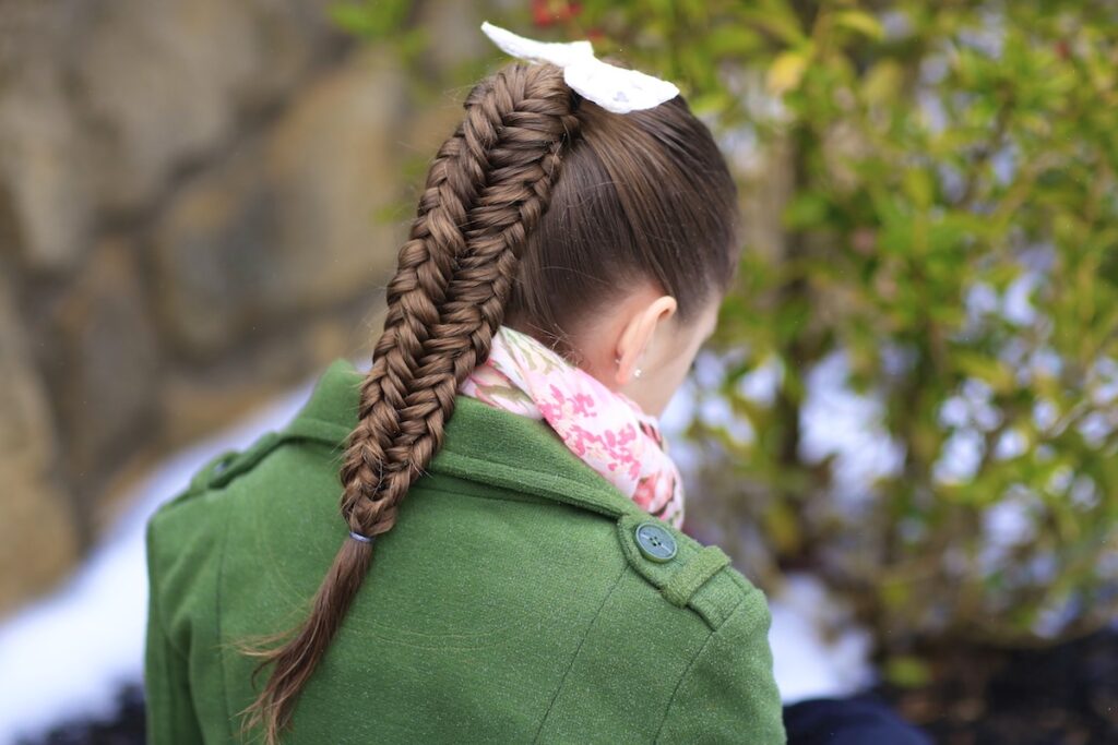 Young girl outside in a winter coat modeling Twisted Edge Fishtail Combo | Braid and Updo