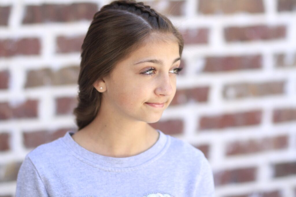 Young girl standing outside modeling Peek-a-Boo Tuxedo Braid