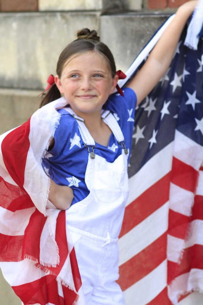 Little girl holding American flag modeling Star Bun Combo | 4th of July Hairstyles