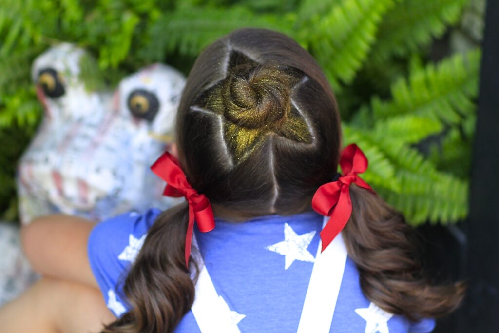 Little girl sitting outside modeling Star Bun Combo | 4th of July Hairstyles