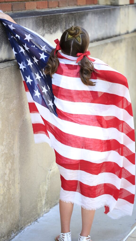 Little girl holding American flag modeling Star Bun Combo | 4th of July Hairstyles