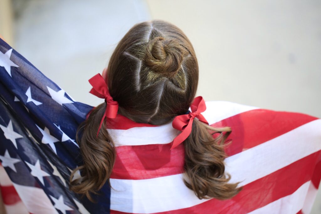 Little girl holding American flag modeling Star Bun Combo | 4th of July Hairstyles