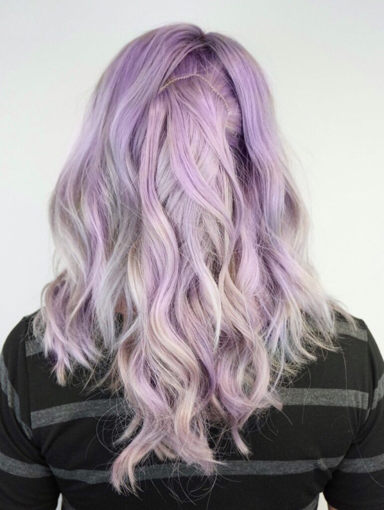 Back view of a girl with lavender curly hair in front of a white background