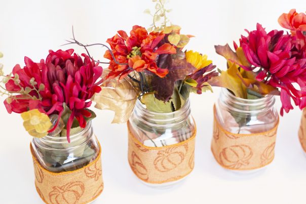 Fall flowers place inside mason jars wrapped with fall themed ribbon