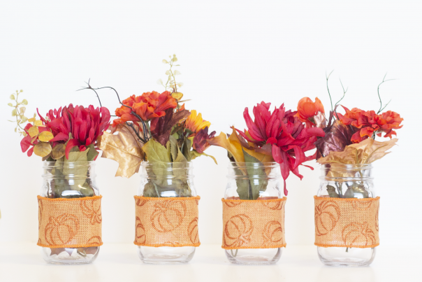 Fall flowers place inside mason jars wrapped with fall themed ribbon