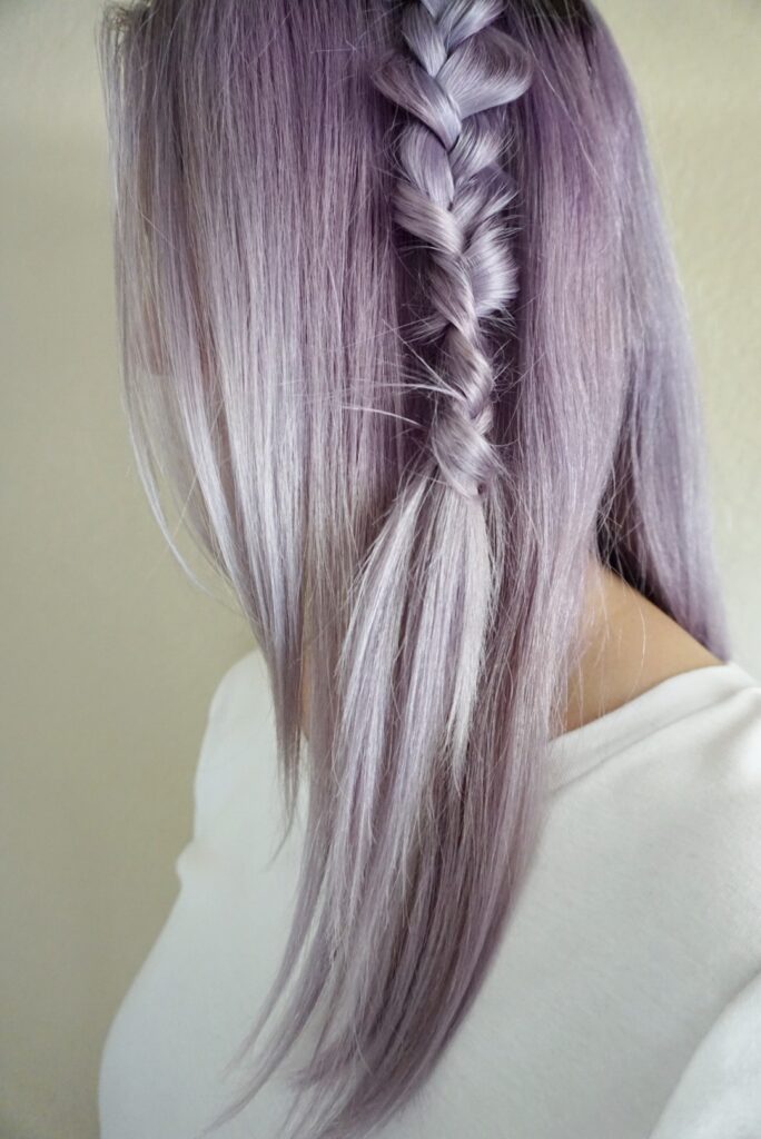 Woman with lavender dyed hair wearing a white shirt showing her braid