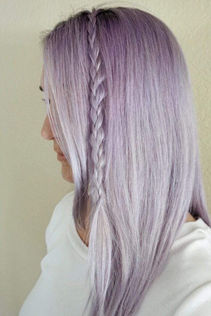 Woman with lavender dyed hair wearing a white shirt showing her braid