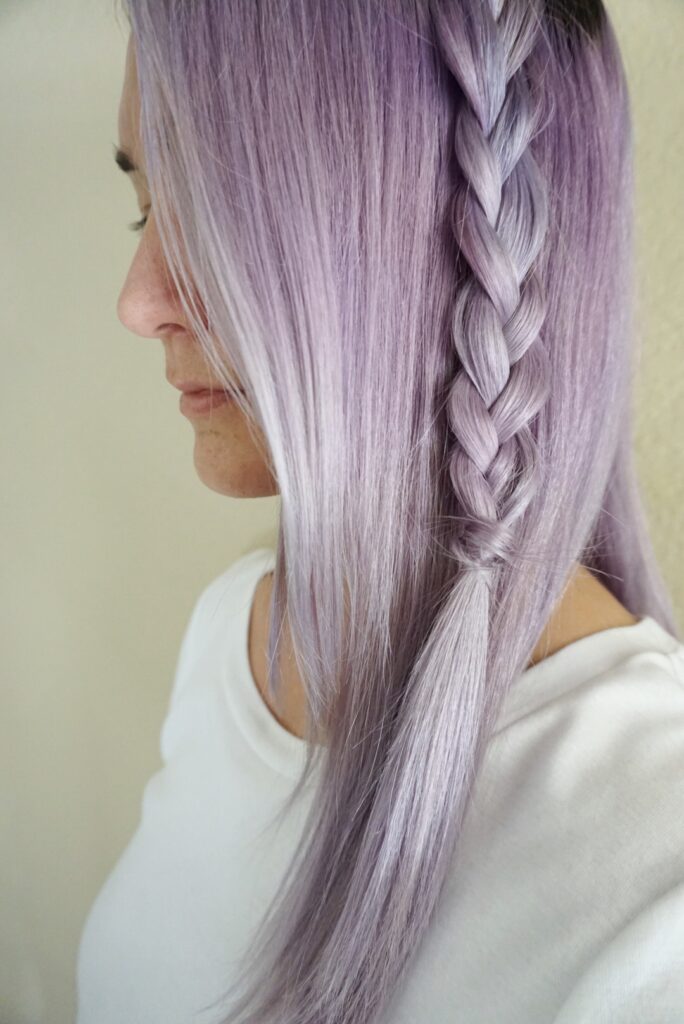 Woman with lavender dyed hair wearing a white shirt showing her braid