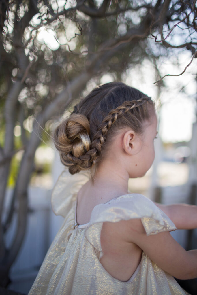 Side view of a little girl outside modeling "Braided Bun" hairstyle