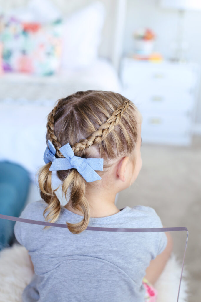 Back view of little girl sitting in her room modeling "Criss Cross Pigtails" hairstyle 