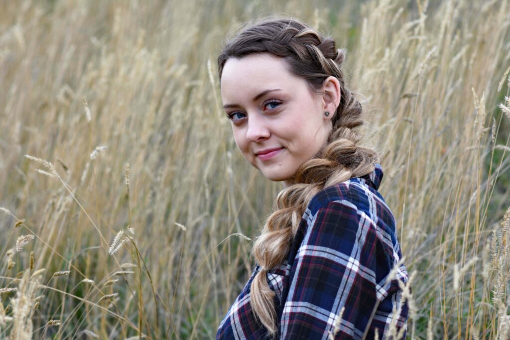 Profile of a young girl with long hair smiling, outside in the meadow 