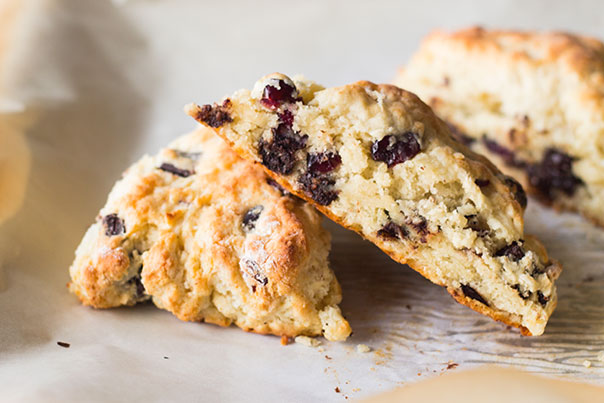 Three cherry and chocolate scones placed on a white parchment paper
