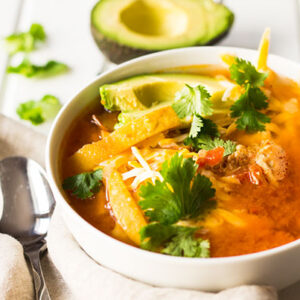 Chicken Tortilla Soup served in a white bowl next to a spoon