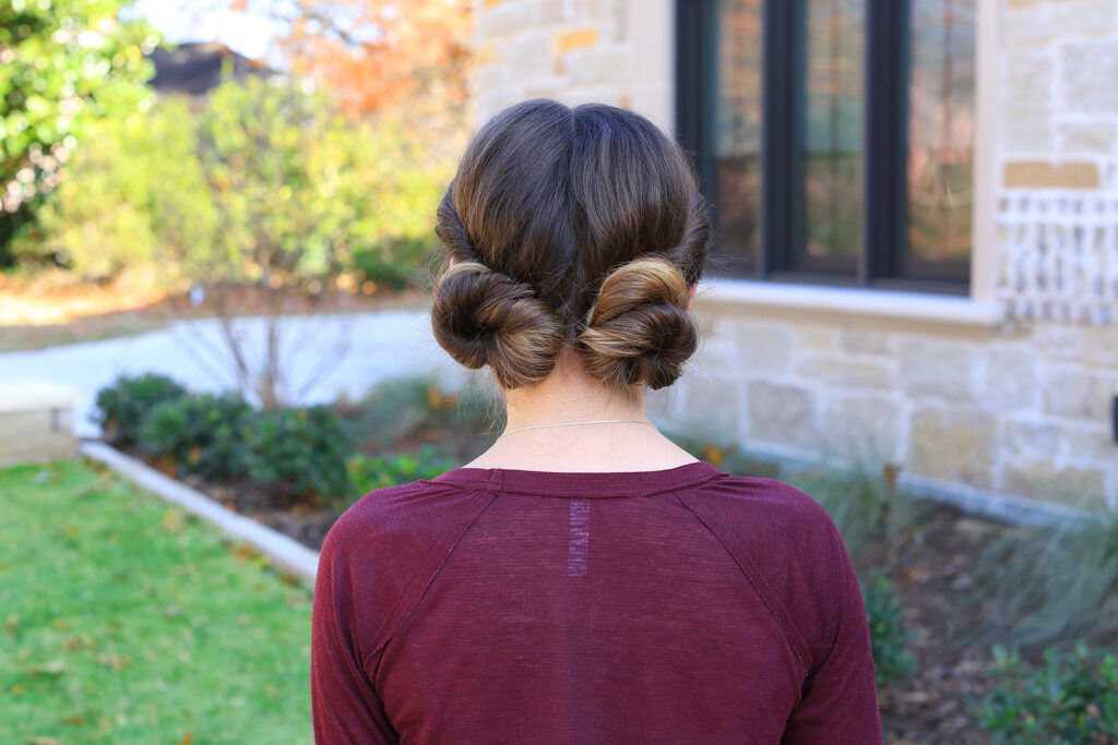 Back view of girl with burgundy shirt outside modeling "Twist Back Buns" hairstyle