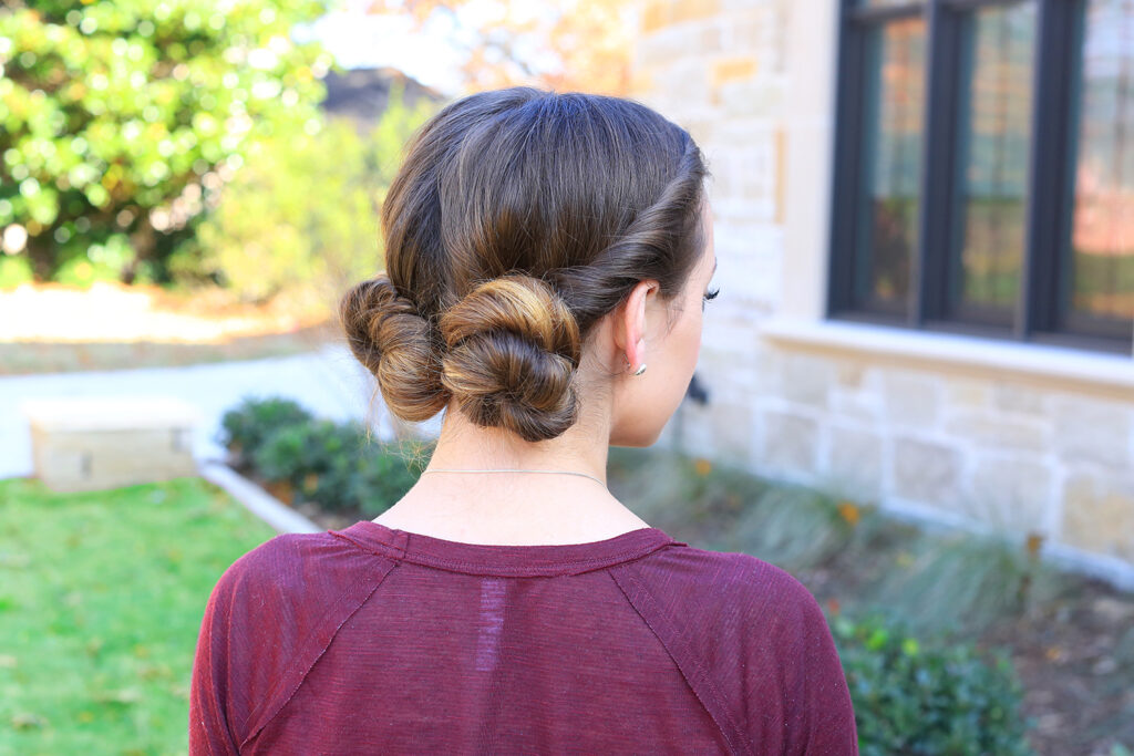 Side view of girl with burgundy shirt outside modeling "Twist Back Buns" hairstyle