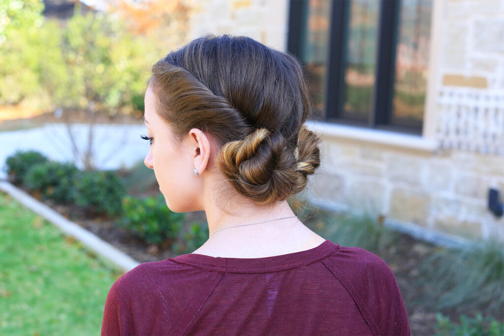 Side view of girl with burgundy shirt outside modeling "Twist Back Buns" hairstyle