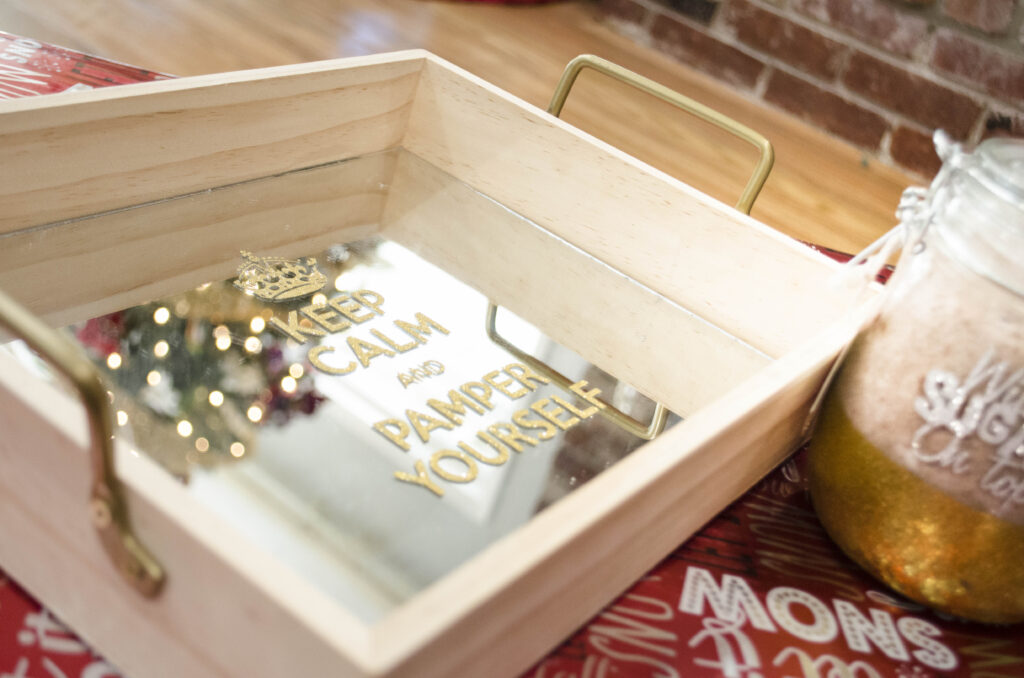 A mirrored serving tray 'Keep Calm and Pamper Yourself' placed on top of Christmas presents