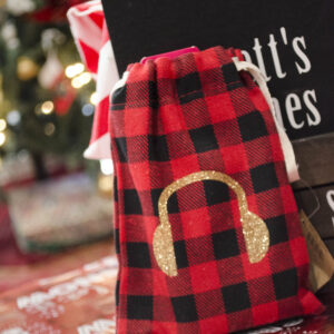 Red and black plaid bag with a gold 'headphones' icon, placed in front of a black sketch journal