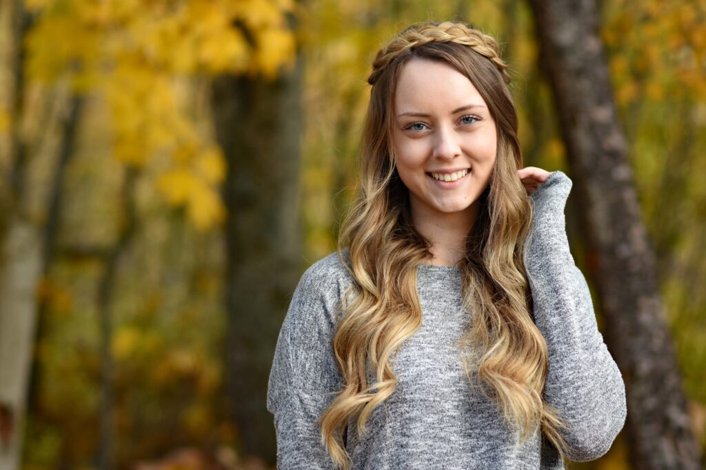 Portrait of a young girl touching her long hair while standing outside 