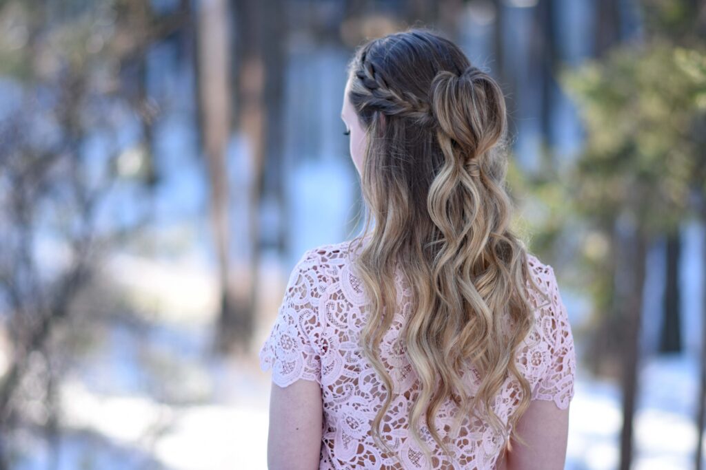 Back view of young girl wearing pink shirt modeling "Half Up Heart Bun" hairstyle