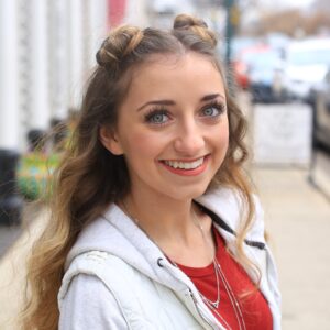 Portrait of a young girl with a long hair smiling standing on sidewalk