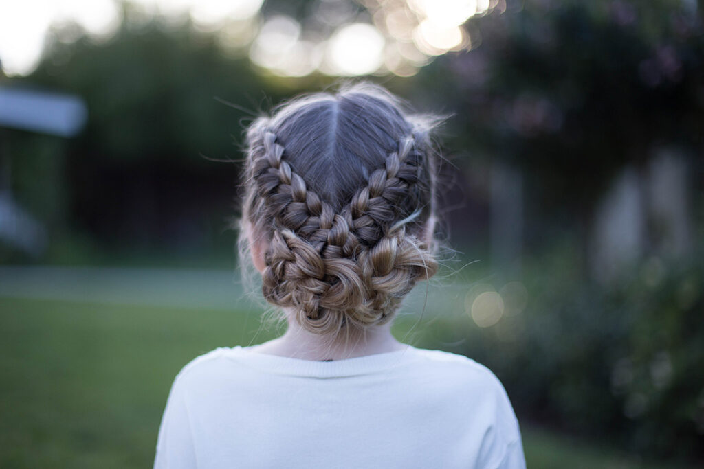 Back view of a young girl standing outside modeling "Flip Over Braid" hairstyle