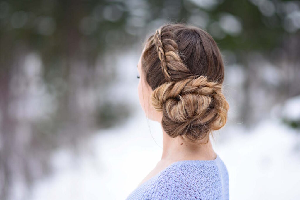 Back view of a girl in a purple shirt, standing outside modeling a "Stacked Fishtail Updo" hairstyle