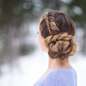 Back view of girl in a purple shirt, standing outside modeling a "Stacked Fishtail Updo" hairstyle