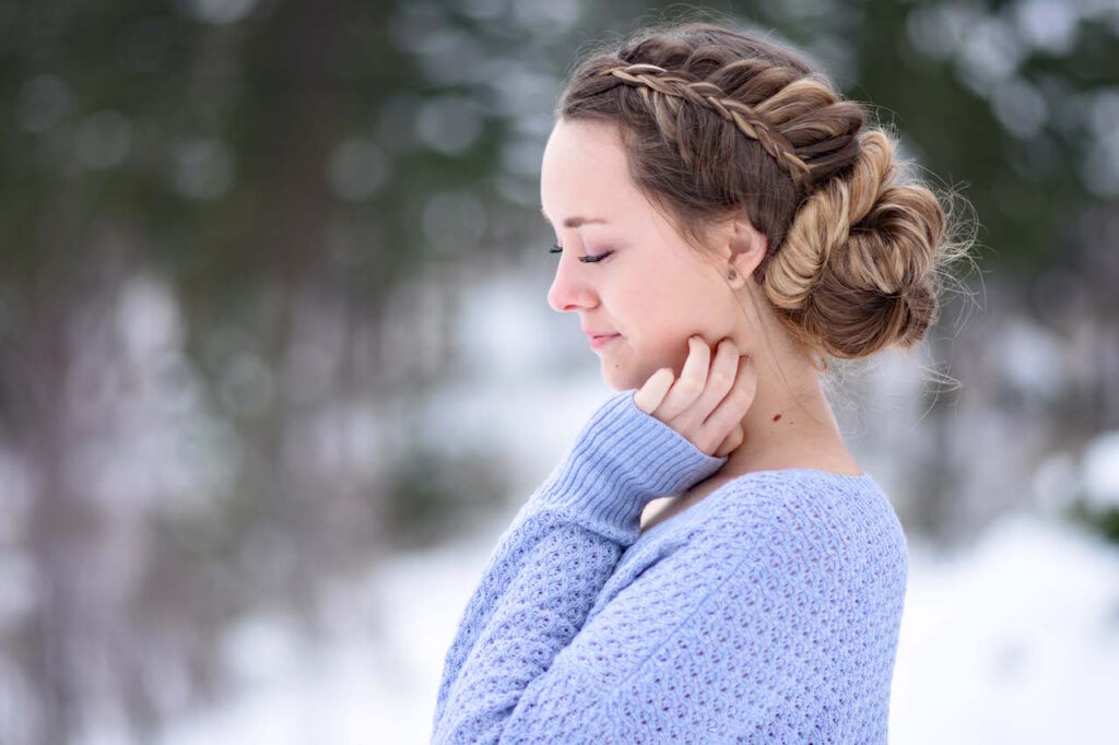 Profile view of a girl in a purple shirt, standing outside modeling a "Stacked Fishtail Updo" hairstyle