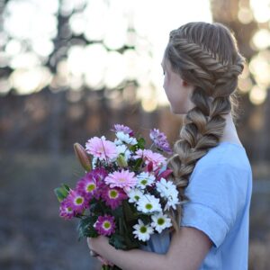 Profile view of a young girls holding flower bouquet modeling "Side Pull-Thru Combo" hairstyle