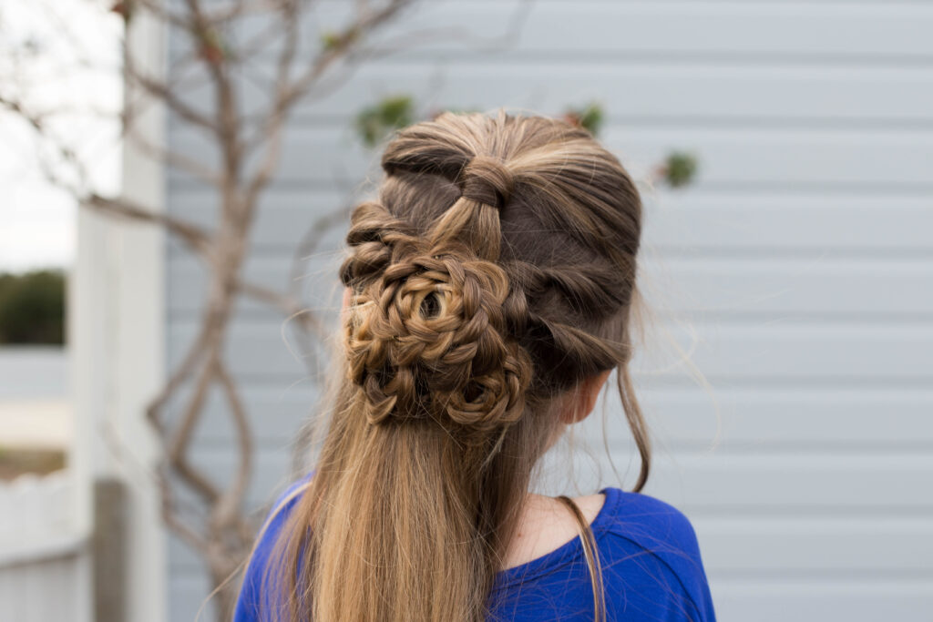 Close up back view of a little girl sitting outside modeling "Flower Half-Up" hairstyle