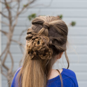 Close up back view of a little girl sitting outside modeling "Flower Half-Up" hairstyle