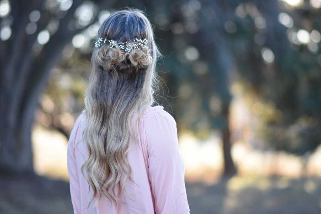 Back view of girl wearing a pink shirt standing outside modeling "Fishtail Half-up" hairstyle