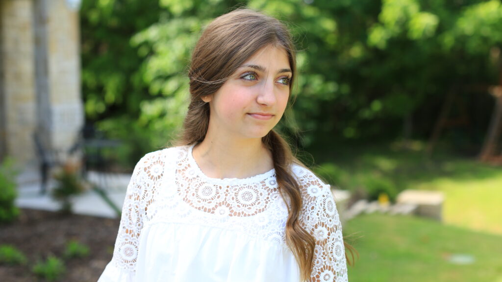 Portrait of young girl smiling and wearing a white shirt standing outside