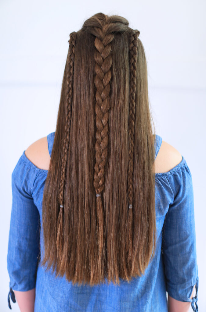 Back view of girl with blue shirt standing indoors modeling the "Dutch Lace Braid Combo" hairstyle