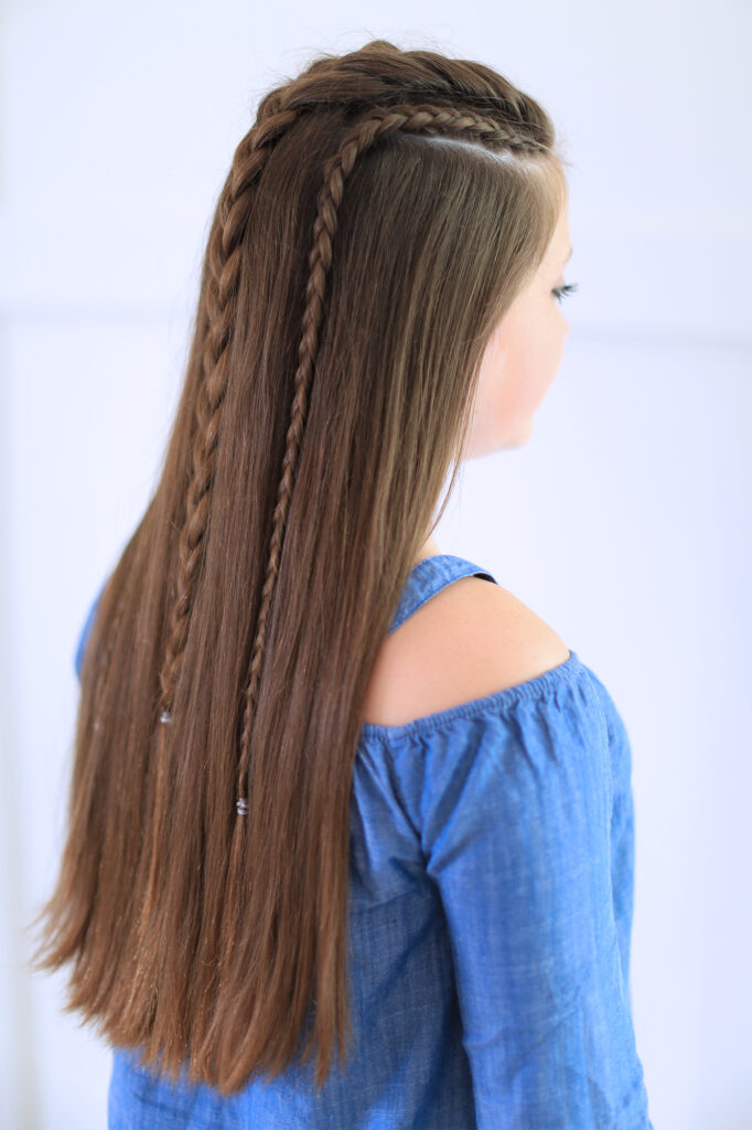 Side back view of girl with blue shirt standing indoors modeling the "Dutch Lace Braid Combo" hairstyle