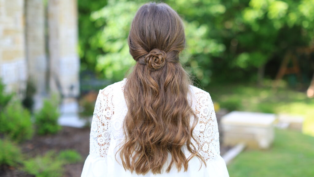 Back view of young girl with long hair standing outside modeling "Rosette Tieback" hairstyle